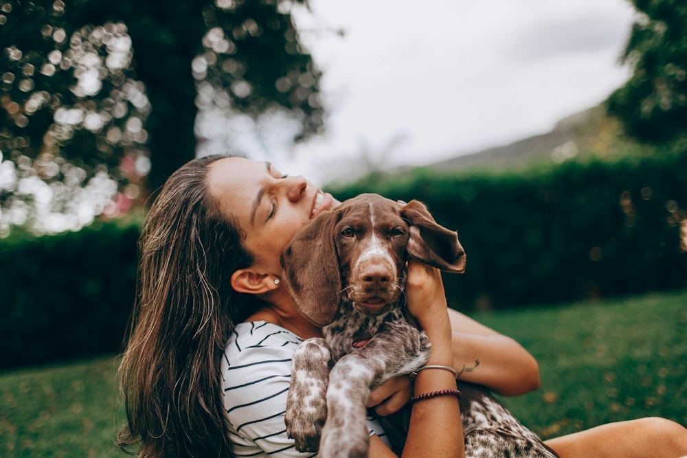 A woman hugging her brown and white dog