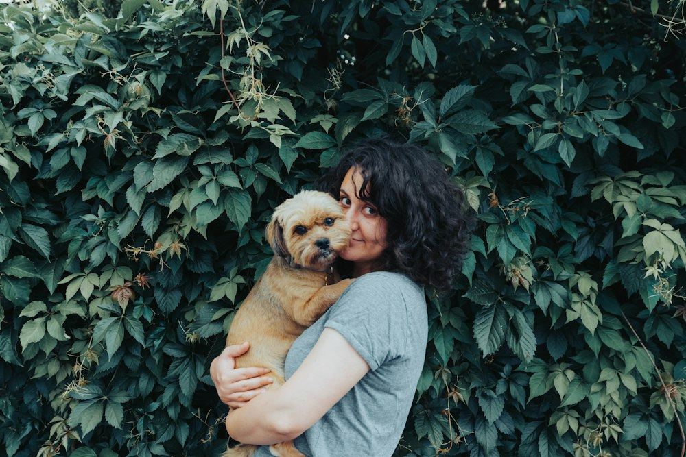 A woman in a grey t-shirt holding her dog close